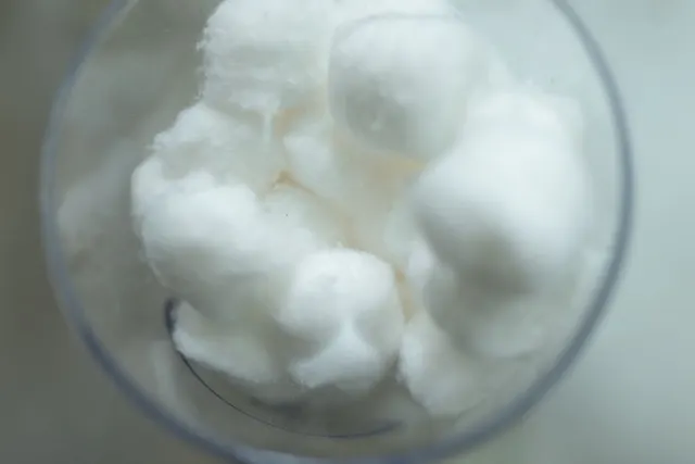 Bolas de algodón blanco amontonadas dentro de un vaso de cristal