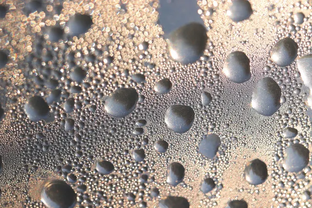 Primer plano de gotas de agua grandes y pequeñas condensadas sobre una superficie de cristal