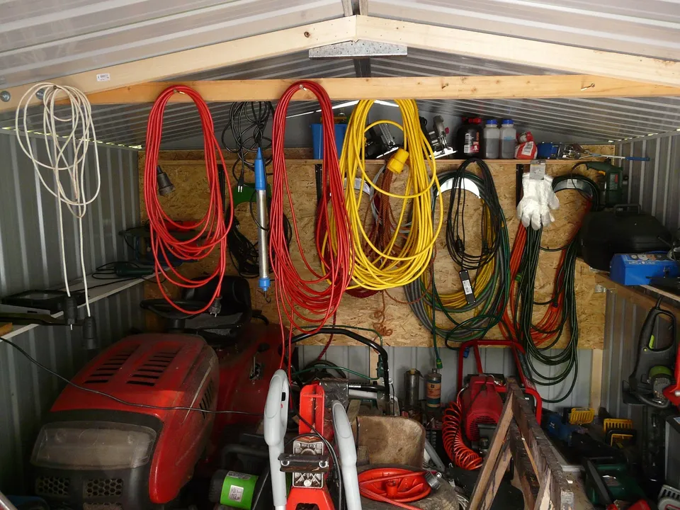 Interior de un garaje con estanterías, cables enrollados y herramientas