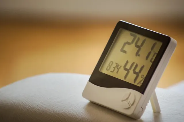 Termohigrómetro digital blanco sobre una superficie clara, con la pantalla marcando 24,1 grados y 44 % de humedad